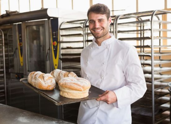 Happy baker showing tray with bread at the bakery ID:82693217